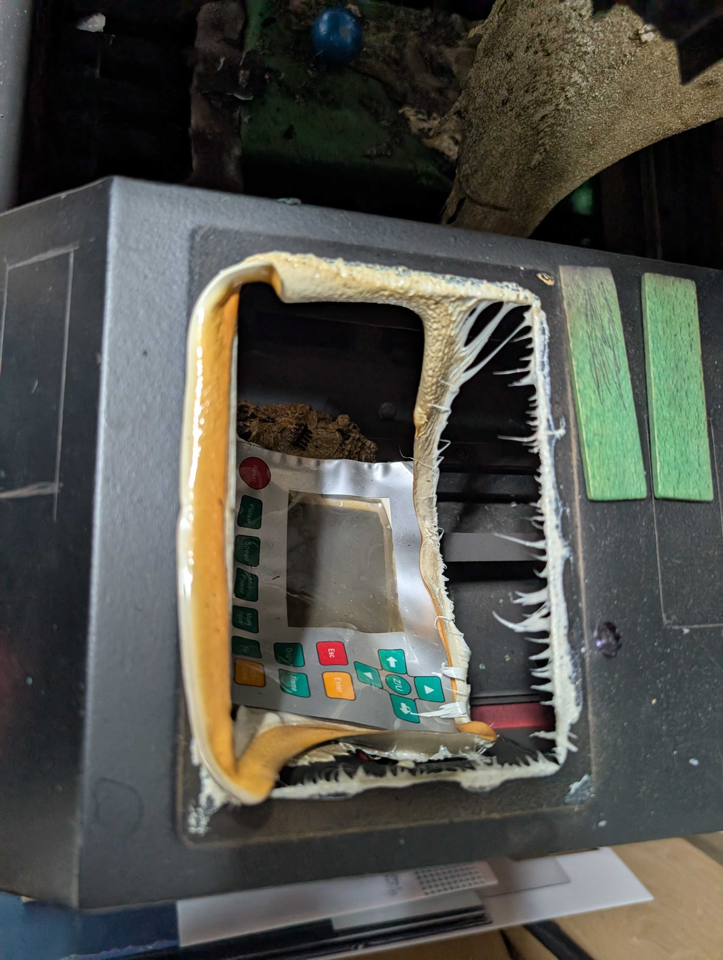 Photo of a melted Ruida controller falling out of the frame of the laser